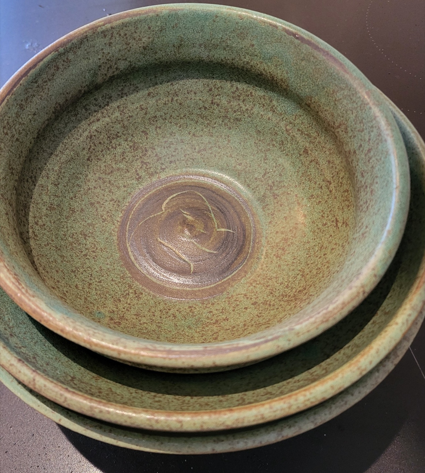 Two stacked stoneware bowls with a celadon glaze and a chop-mark seal at the base of the inner bowl.